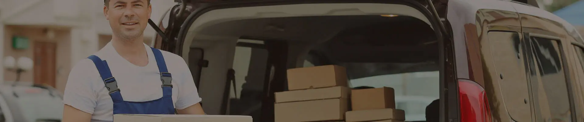 Top Attractions in the Bronx NY: The Best Places to Visit in New York's Northernmost Borough Delivery worker holding a box in front of a van filled with packages, showcasing logistics and shipping services.